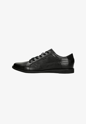 Zwart leren lage veterboot met een gladde afwerking, ronde neus en subtiel gestikt paneelontwerp, gezien vanaf de zijkant op een witte achtergrond.