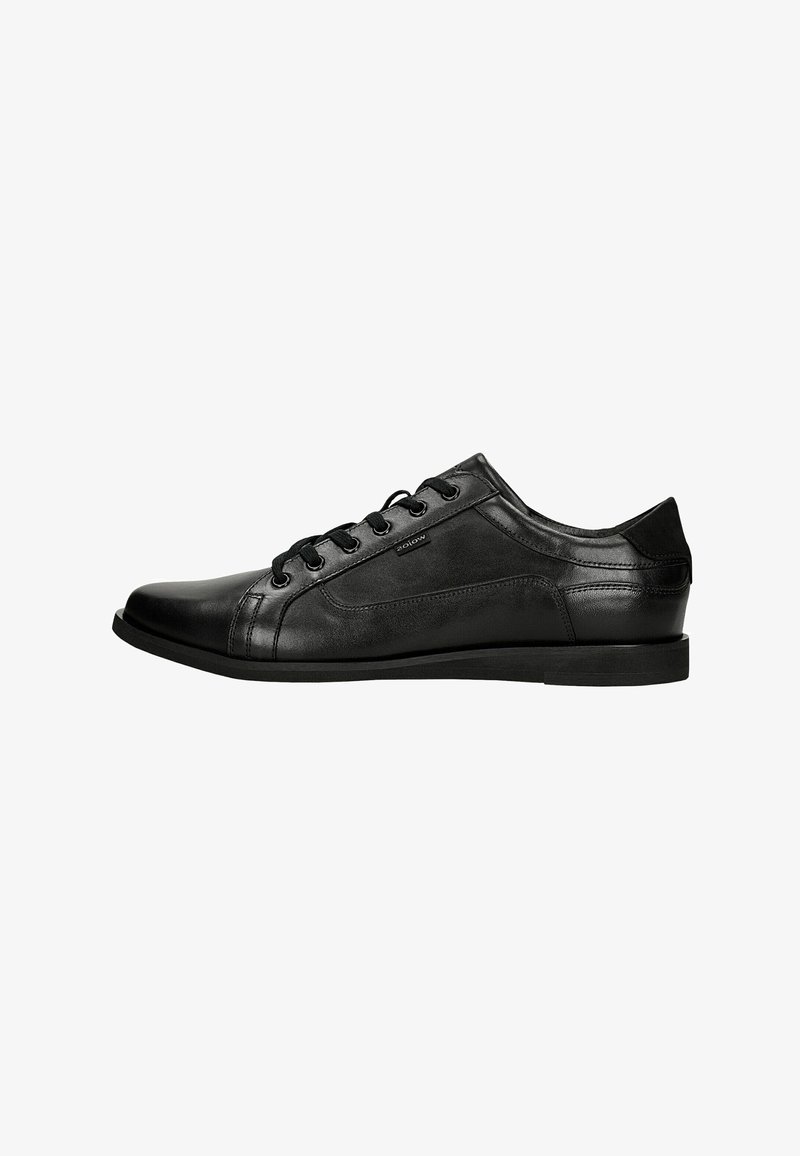 Chaussure basse en cuir noir à lacets, finition lisse, bout rond et design subtil avec des panneaux cousus, vue de profil sur fond blanc.