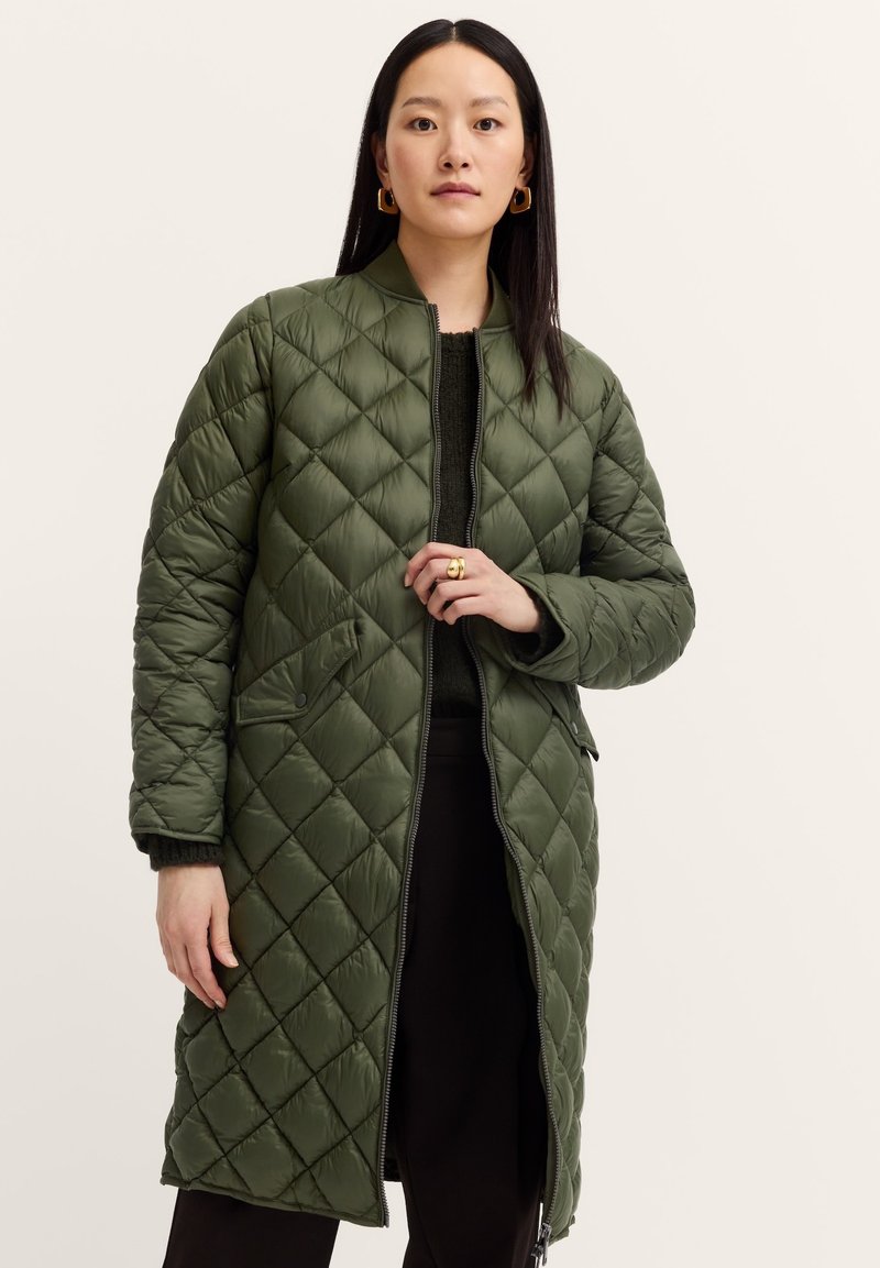 Gepolsterter langer Mantel in Olivgrün mit hohem Kragen, Frontreißverschluss und seitlichen Taschen. Mit einem Rautenmuster und gepolsterter Textur.
