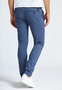 Modré vzorované casual kalhoty s úzkým střihem, vybavené dvěma zadními kapsami a knoflíkovými zapínáními. Vyrobeno z lehkého materiálu, doplněno bílými botami.