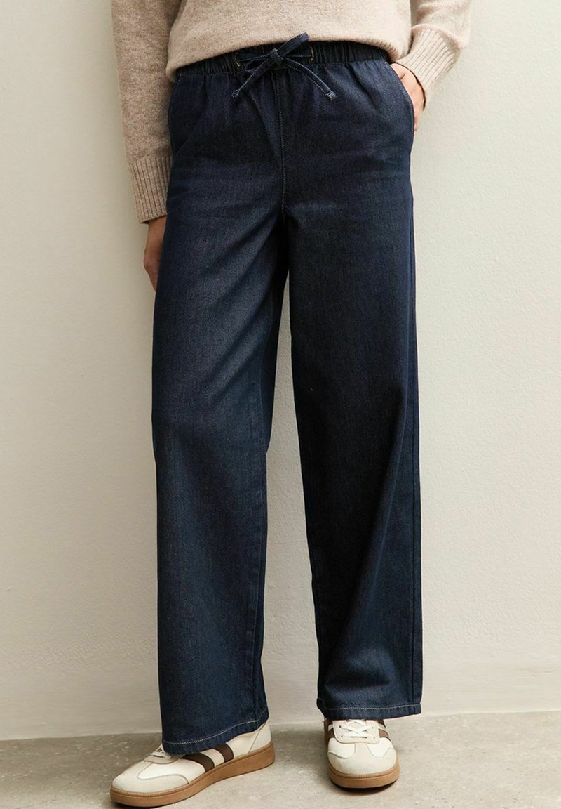 Vaqueros de pierna ancha en azul marino, hechos de denim, con una cinturilla elástica con cordón, bolsillos laterales y una textura suave.