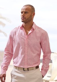 Helles rosa gestreiftes Langarmhemd mit Button-Down-Kragen, aus strukturiertem Stoff gefertigt. Kombiniert mit einem beigen gewebten Gürtel und hellen Hosen.