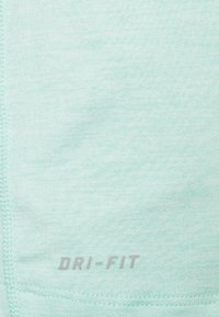 Jasnoniebieska tkanina z widocznym przeszyciem i małym logo "DRI-FIT" nadrukowanym na szaro w pobliżu dolnej krawędzi.