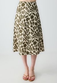 Gonna a trapezio realizzata in tessuto beige, caratterizzata da un audace motivo astratto verde. Lunghezza fino al polpaccio con taglio dritto e orlo svasato.