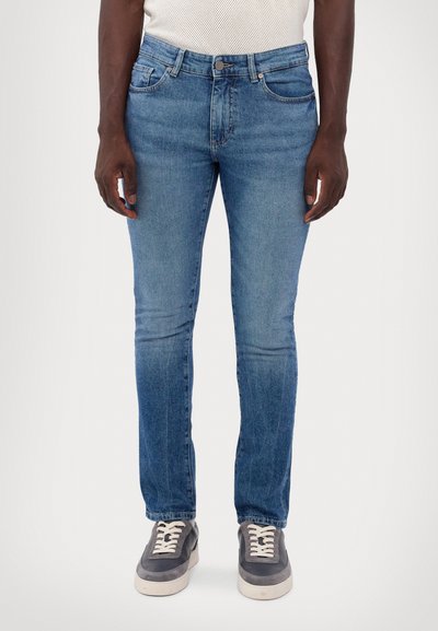 Kék farmernadrág, slim fit szabásban, klasszikus öt zsebes dizájnnal, enyhe fakulással az elülső részen, cipzáras sliccel és gombos záródással.