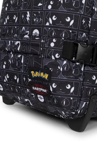 Černý látkový batoh s bílými grafickými panely postav Pokémon. Obsahuje nášivky s logem Eastpak a Pokémon, pevné spony a hladký povrch.
