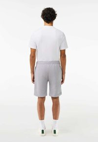 Shorts en coton gris avec une taille élastique et des poches latérales, associés à un t-shirt blanc à manches courtes uni et des baskets blanches.