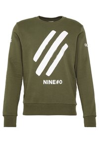 Olivgrön sweatshirt gjord av bomull, med en vit grafik som har tre penseldrag och texten "NINE#0" tryckt nedanför.