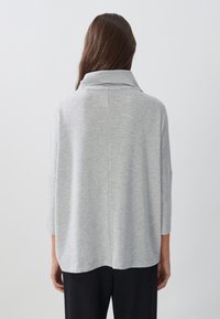 Grauer, übergroßer Pullover mit hohem Kragen, Dreiviertelärmeln und einer weichen Textur. Verfügt über einen geraden Saum und minimale Nähdetails.