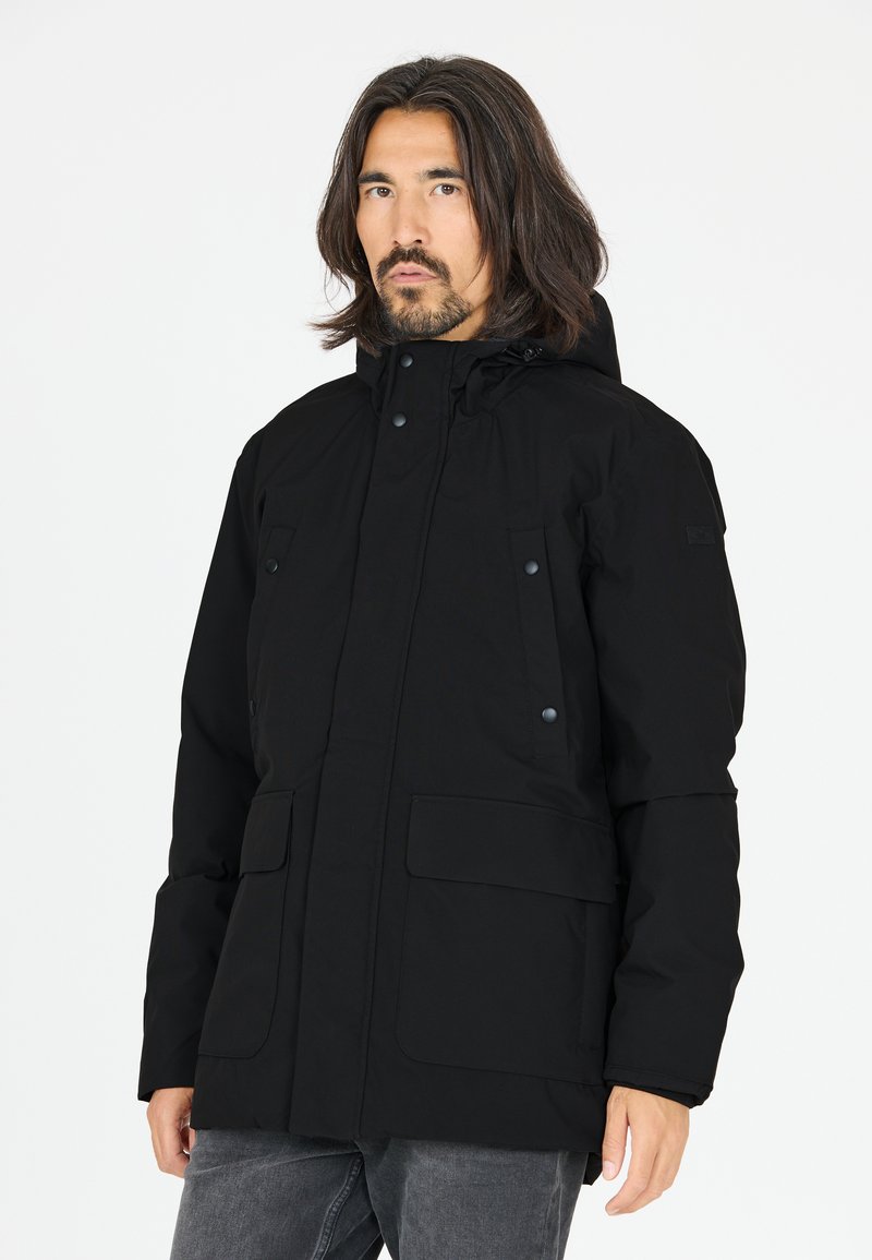 Sort vandtæt jakke med hætte, fronttryklåse og to store frontlommer. Materialet ser glat og holdbart ud.