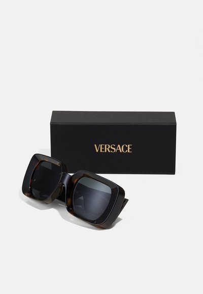 Versace överdimensionerade solglasögon med ram i sköldpaddsmönster, mörka linser och vinkelriktig design. Packeterade i en svart låda med guldtext.