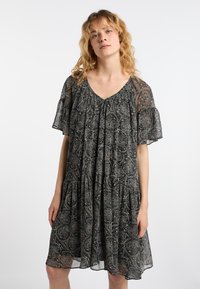 Musta kuviollinen mekko lyhyillä hihoilla, v-pääntiellä ja kerroksella rypytetty helma. Sisältää monimutkaisia paisley-kuvioita teksturoidussa kankaassa.