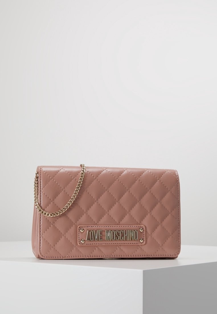 Prošívaná růžová kabelka ze syntetické kůže se zlatým řetízkem a logem. Obdélníkový tvar s uzávěrem na klapku a detailem v podobě diamantového vzoru.