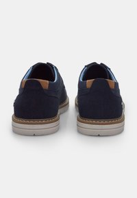 Pantofi din suede navy cu căptușeală albastră deschisă, accente de toc bej și tălpi de culoare crem. Prezintă un design cusut pe marginea tălpii.