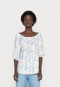 Blusa leve, com ombros à mostra, em um padrão de tie-dye azul e branco. Apresenta mangas de três quartos com punhos elásticos e um ajuste relaxado.