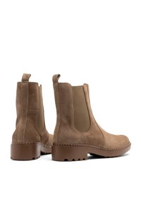 Botas Chelsea de nobuk marrón con paneles elásticos en los laterales, punta redonda y suelas de goma texturizada. Cuenta con pestañas para facilitar su puesta.