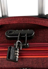 Maleta de tela roja con cerradura de combinación, cremallera metálica y doble tirador. Superficie texturizada con acentos de cremallera naranja en contraste.