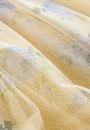 Durchscheinender, leichter Stoff mit einem sanften gelben Grundton und floralen Mustern in Blau und Grün. Strukturiertes Netzgewebe sorgt für Tiefe und visuelles Interesse.