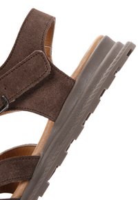 Sandalo in suede marrone con cinturino in velcro e suola spessa in gomma. La vista laterale mostra la parte superiore texturizzata e foderata internamente liscia.
