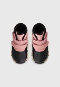 Zapatos infantiles en negro y rosa con doble correa de Velcro, punta redondeada y forro texturizado negro. Suela de goma con patrón de relieve para mayor agarre.