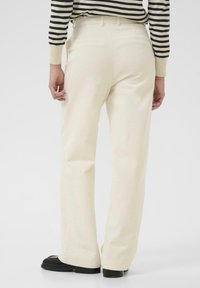 Ecru corduroy flared broek met zichtbare ribbelstructuur en twee achterzakken. Gepaard met zwarte platform schoenen.
