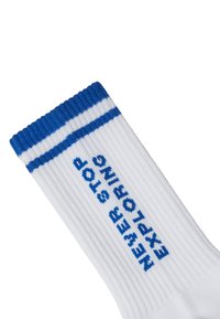 Białe bawełniane skarpetki o prążkowanej strukturze, z niebieskim paskiem na górze i haftowanym napisem "NIGDY NIE PRZESTAWAJ EKSPLOATOWAĆ" w kolorze niebieskim.