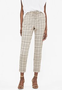 Pantalons à carreaux beiges avec une taille élastique et un cordon de serrage, présentant une jambe cintrée et des poignets retroussés. Tissu lisse et léger.