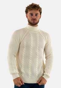 Suéter de punto trenzado color crema con cuello alto, que presenta un acabado de canalé y patrones texturizados, elaborado con un material cálido y grueso.