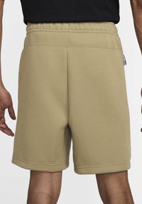 Beiga bomullsshorts med elastisk midja, sidofickor och rak skärning. Slät textur och sömdetaljer vid fållen.