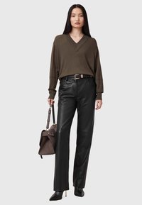 Maglione oversize verde oliva a V; pantaloni in pelle nera a gamba dritta; borsa marrone con tracolla; stivaletti neri con tacco a spillo.