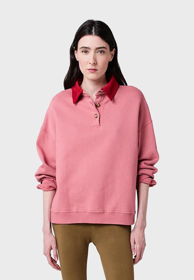 Rosa sweatshirt med röd krage, tre-knappsingång, oversized passform och ribbade mudd. Slät textur med en avslappnad design.