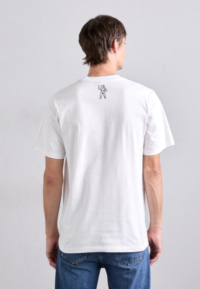 Tricou alb din bumbac, cu o croială relaxată, având o grafică mică cu un astronaut negru pe spate, aproape de guler. Mâneci scurte, textură netedă.