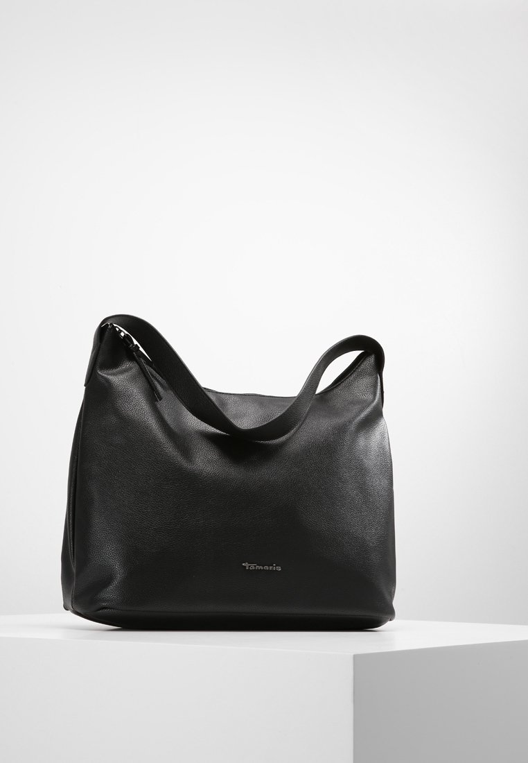 Sac à bandoulière en cuir noir avec une seule bandoulière et un logo discret sur le devant, présenté sur un socle blanc sur un fond uni.