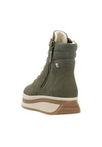 Bottine en suède vert avec doublure en fausse fourrure, fermeture à lacets et zip, et une semelle compensée contrastante blanche et beige. Tige texturée avec détails de couture.