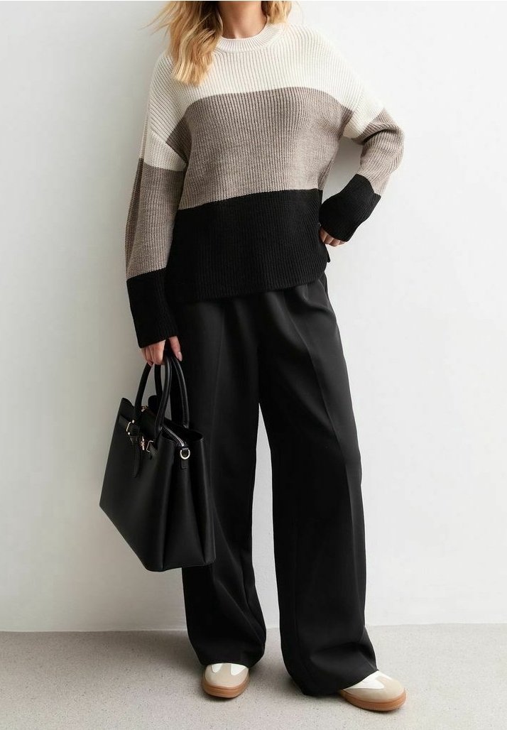 Stickad tröja i beige, krämfärgad och svart färgblockdesign; kombinerad med svarta vida byxor och en svart handväska. Skor i kräm och tan-färgad.