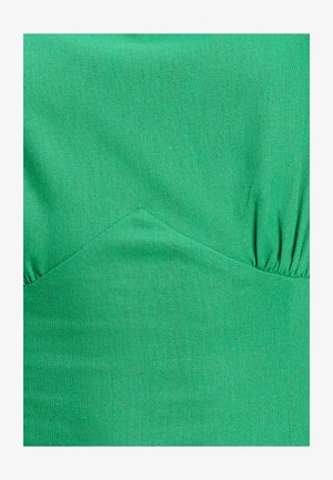 Grüner Stoff mit einer glatten Textur, der ein enganliegendes Design und geraffte Details an den Seiten aufweist. Die Farbe ist lebhaft und gleichmäßig verteilt.