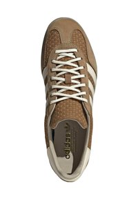 Sneaker con esterno in suede marrone, tessuto testurizzato, accenti a strisce bianche e rivestimento interno color crema; presenta lacci piatti e logo dorato.