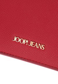 Portafoglio in pelle rossa con texture, caratterizzato da un logo in oro stampato "JOOP! JEANS" e cuciture visibili lungo i bordi.