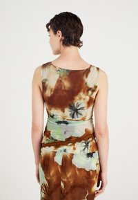 Ermeløs kjole i lys brun og grønn blomsterdesign, med en figurnær silhuett og myk, teksturert stoff med rynket midje.