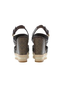 Brown wedge sandals with adjustable ankle strap, featuring patterned textile heel, braided jute midsole, and logo detail on the sole.