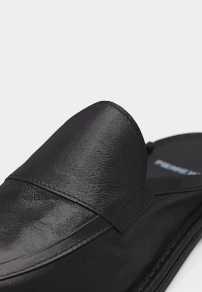 Κοντινό πλάνο μαύρου δερμάτινου παπουτσιού τύπου loafer με ραφές και λείο στρογγυλεμένο μύτη.