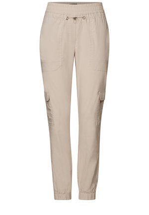 Pantaloni cargo beige con vestibilità morbida, fascia elastica in vita, chiusura con cordino e numerose tasche laterali. Materiale in cotone liscio.