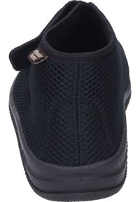 Black mesh shoe with a flexible fabric upper, reinforced heel, and textured rubber sole. Features a hook-and-loop strap for easy wear.