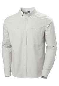 Camisa de manga larga gris claro con cuello abotonado, dos bolsillos en el pecho y una tela suave y texturizada. Cuenta con cierre frontal de botones.