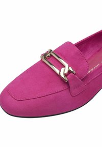 Mocassin en daim rose avec un accent en chaîne dorée, présentant un bout arrondi et des coutures le long du bord.