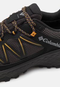 Czarne buty sportowe z żółtymi akcentami, wykonane z materiału kompozytowego z siateczki, z fakturowaną gumową podeszwą; posiadają okrągłe sznurowanie i detal z logo.