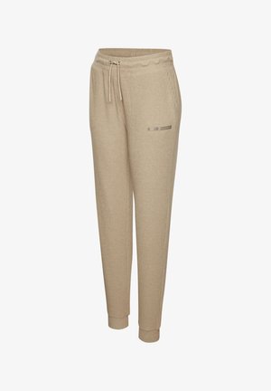 Beige ribbed jogger pants with elastic waistband, drawstring, side pockets, cuffed ankles, and small brand patch on front right thigh.
