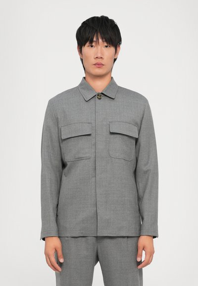 Grau karierter Anzugjacke mit Kragen, zwei Brusttaschen, einem strukturierten Stoff und langen Ärmeln, kombiniert mit passenden Hosen.