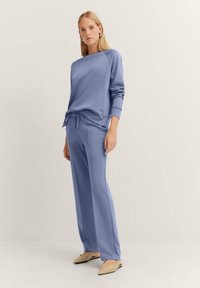 Light blue sweatshirt with a relaxed fit and crew neckline, paired with matching drawstring pants. Simple design with a smooth texture.