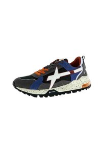 Chaussure de sport multicolore présentant un mélange de matériaux noirs, gris, bleus et rouges, avec une semelle mouchetée et des accents orange.
